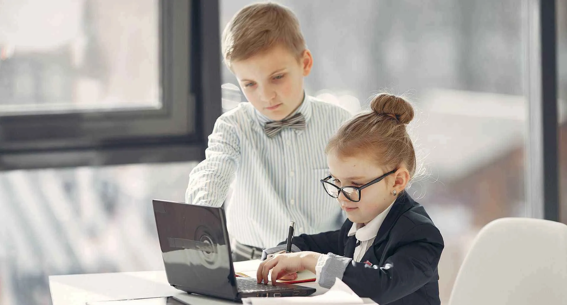 Two children dressed like executives working at a desk
